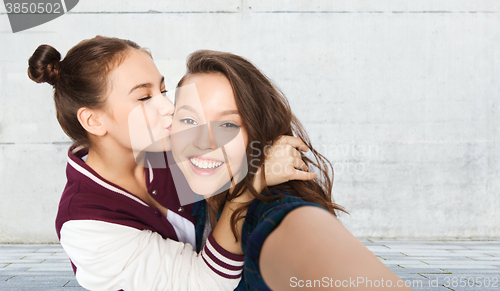 Image of happy teenage girls taking selfie and kissing