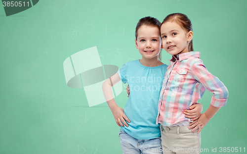 Image of smiling girls hugging over green school board
