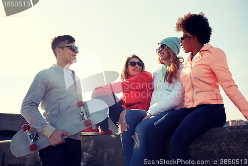 Image of happy teenage friends with skateboard on street