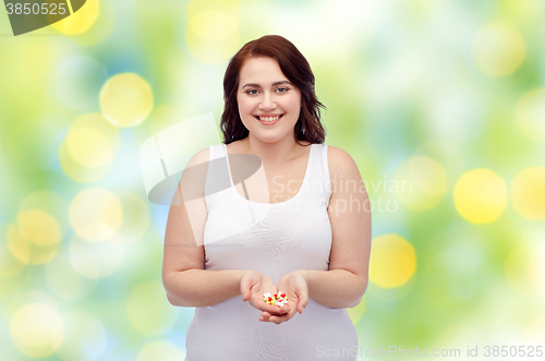 Image of happy plus size woman in underwear with pills