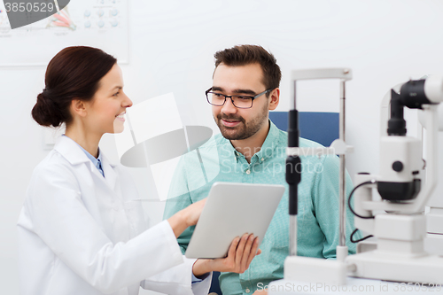 Image of optician with tablet pc and patient at eye clinic