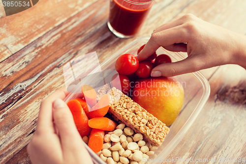 Image of close up of hands with vegetarian food in box
