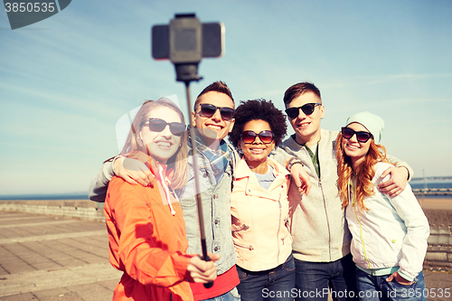 Image of smiling friends taking selfie with smartphone