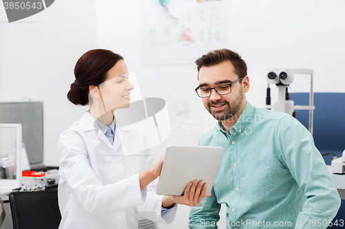 Image of optician with tablet pc and patient at eye clinic