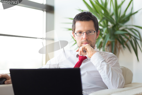 Image of Portrait of businessman working on laptop computer