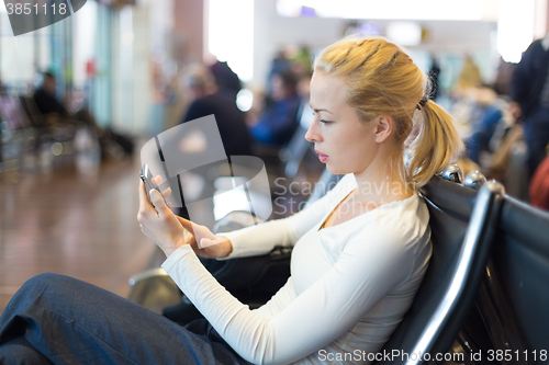Image of Female traveler using cell phone while waiting.