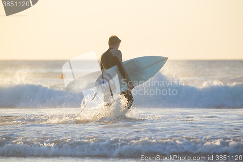 Image of Silhouette of surfer on beach with surfboard.