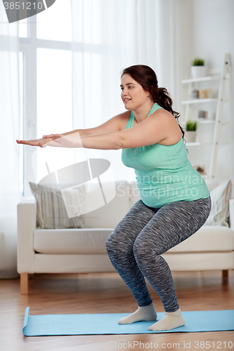 Image of plus size woman exercising on mat at home