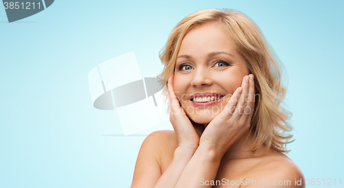 Image of smiling woman with bare shoulders touching face