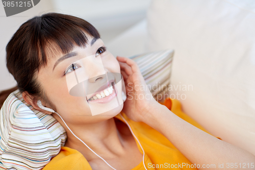 Image of happy asian woman with earphones listening music