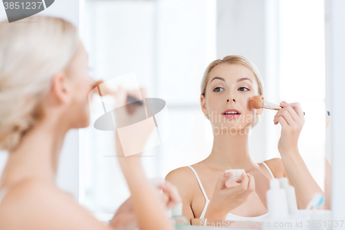 Image of woman with makeup brush and powder at bathroom