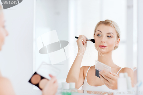 Image of woman with makeup brush and foundation at bathroom