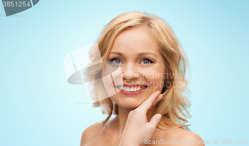 Image of smiling woman with bare shoulders touching face