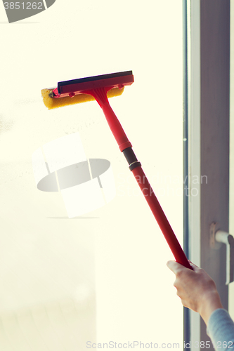 Image of close up of hand cleaning window with sponge