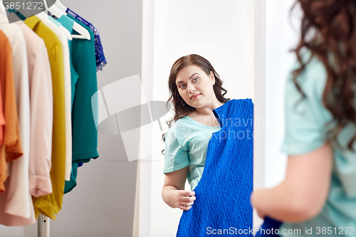 Image of happy plus size woman with dress at mirror