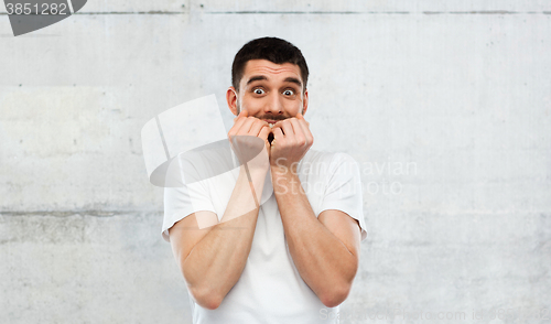 Image of scared man in white t-shirt over gray wall