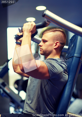 Image of man exercising and flexing muscles on gym machine