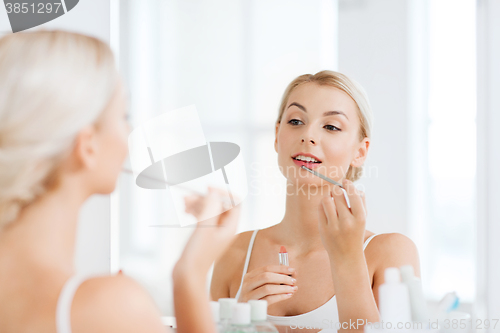 Image of woman with lipstick applying make up at bathroom