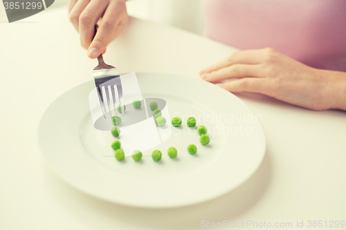 Image of close up of woman with fork eating peas