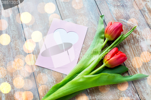 Image of close up of tulips and greeting card with heart