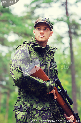 Image of young soldier or hunter with gun in forest