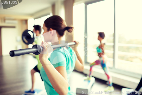 Image of close up of people exercising with bars in gym