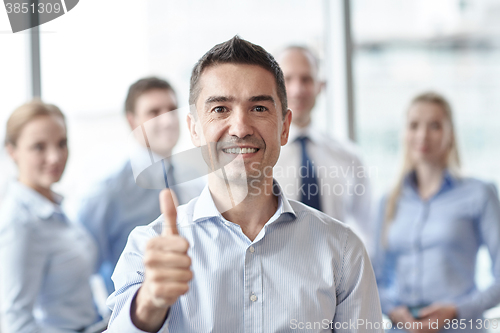 Image of smiling business team showing thumbs up in office
