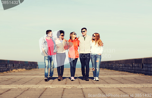 Image of happy teenage friends walking along city street
