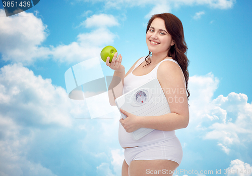 Image of happy young plus size woman holding scales