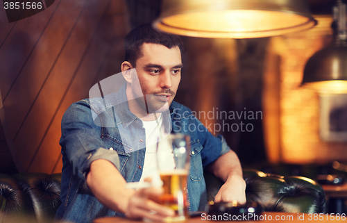 Image of man drinking beer and smoking cigarette at bar