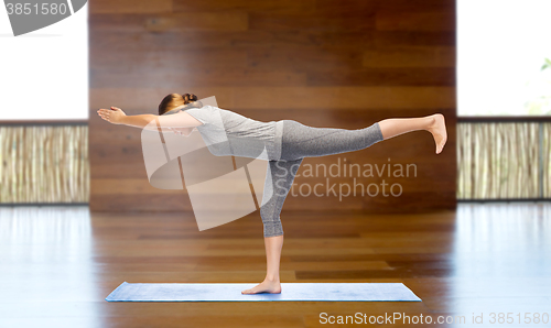 Image of woman making yoga warrior pose on mat