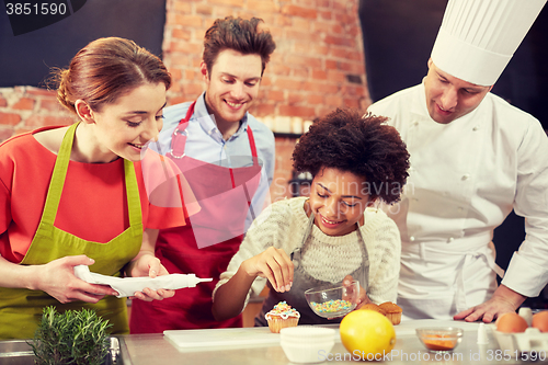 Image of happy friends and chef cook baking in kitchen