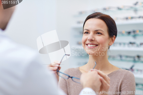 Image of woman taking glasses from optician at optics store