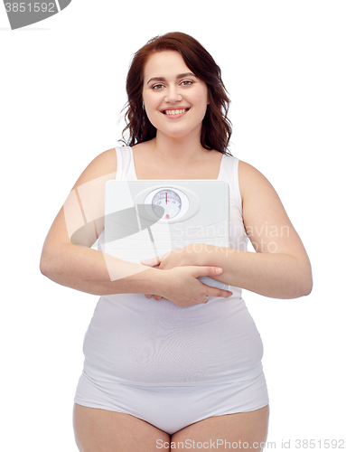 Image of happy young plus size woman holding scales