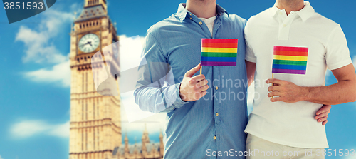 Image of close up of male gay couple with rainbow flags