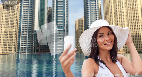 Image of young woman taking selfie with smartphone