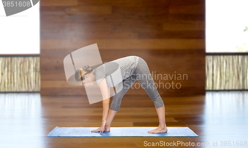 Image of woman making yoga intense stretch pose on mat