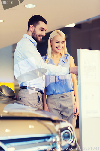 Image of happy couple buying car in auto show or salon