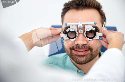 Image of optician with trial frame and patient at clinic