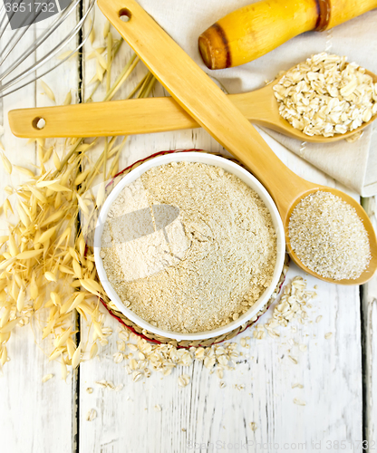 Image of Flour oat in white bowl with bran and flakes on light board