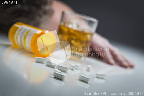 Image of Passed Out Man Behind Scattered Drugs and Glass of Alcohol