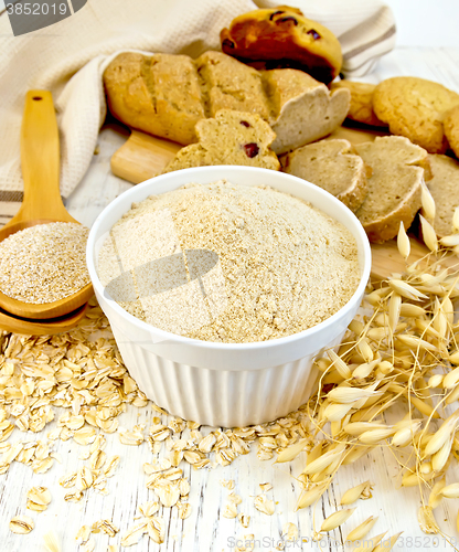 Image of Flour oat in white bowl with bran in spoon on board