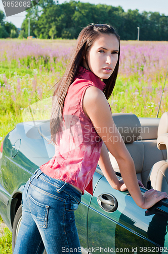 Image of Beautiful brunette female standing near car