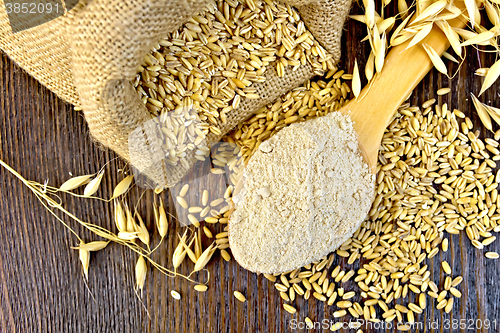 Image of Flour oat in spoon with grain on board top