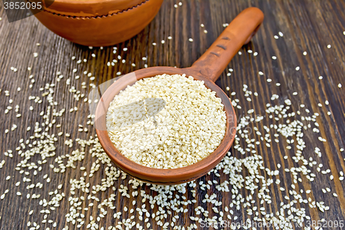 Image of Sesame seeds in clay ladle on board