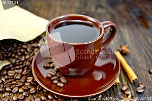 Image of Coffee in brown cup with cinnamon and bag on board
