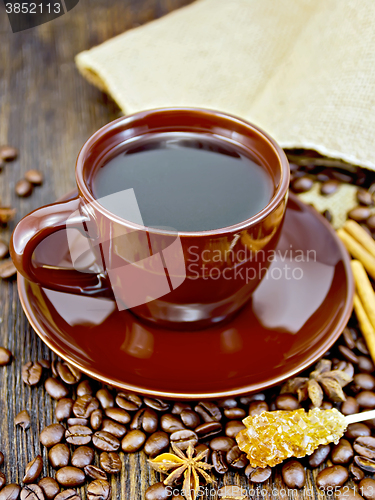 Image of Coffee in brown cup with sugar and bag on dark board