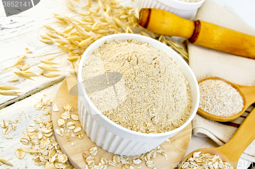 Image of Flour oat in white bowl with flakes on light board