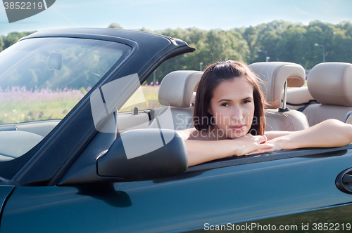 Image of Beautiful brunette female sitting in car