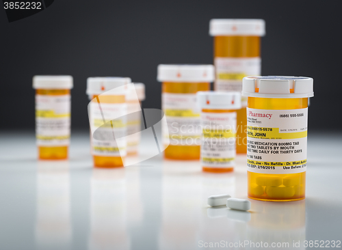 Image of Medicine Bottles and Pills on Reflective Surface With Grey Backg